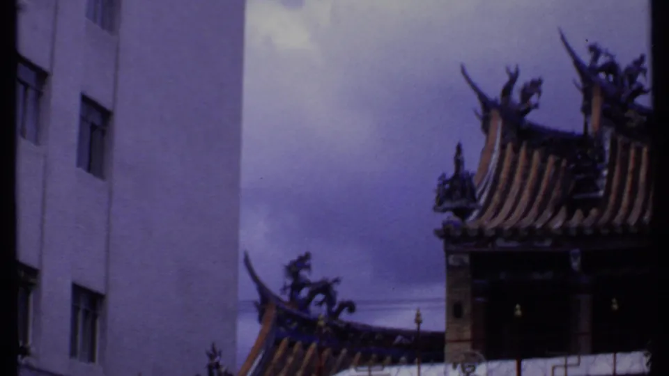 1969 India 8mm frame with a modern white facade framed by ornate Asian-style roof edges.