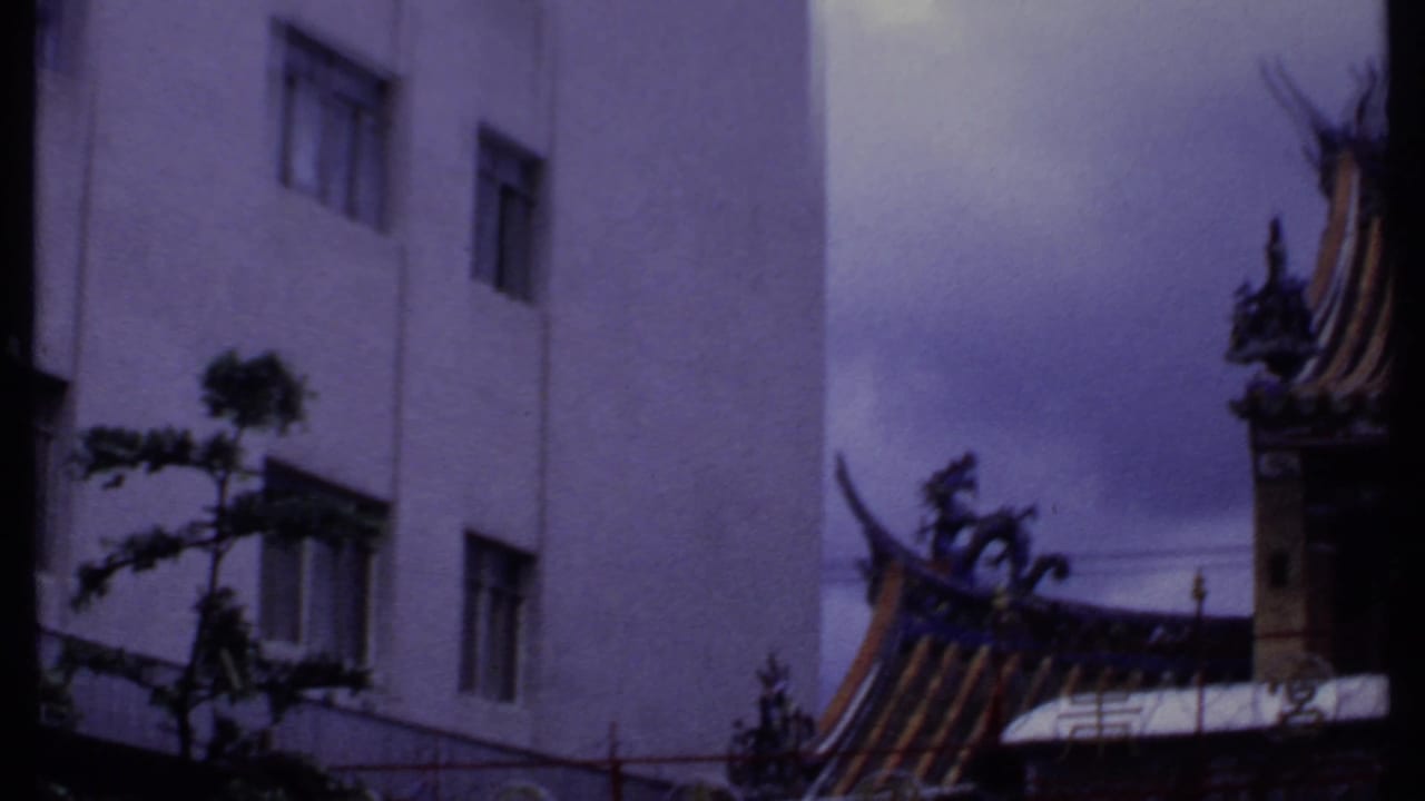 1969 India 8mm frame showing building windows, street foliage, fencing, and a partial ornate roofline.