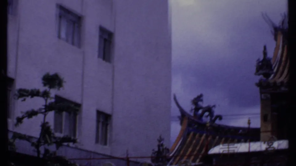 1969 India 8mm frame showing building windows, street foliage, fencing, and a partial ornate roofline.