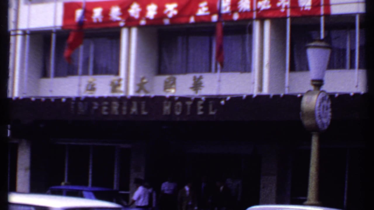 Imperial Hotel facade with Chinese signage, red banner, pedestrians, cars, and a street clock.