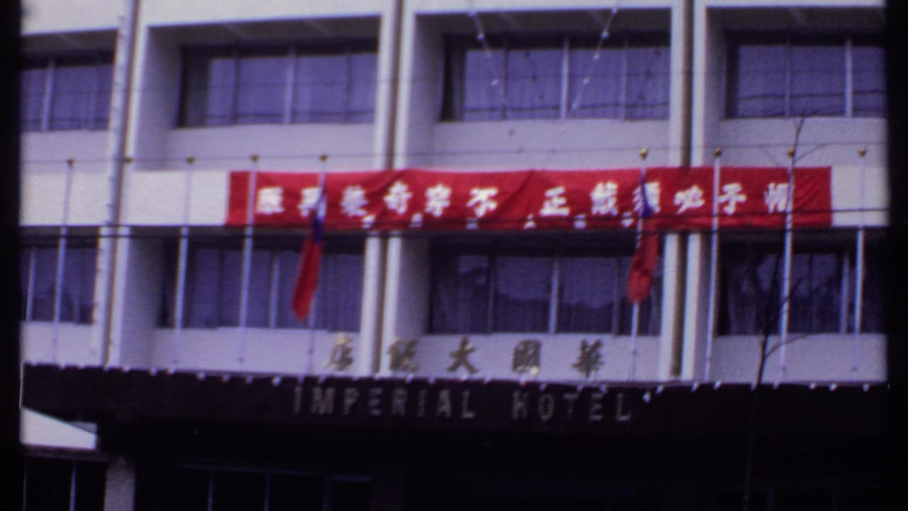 Imperial Hotel entrance area with red banner, Chinese script, windows, and flags.