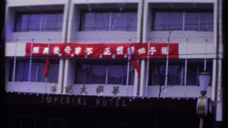 1969 India hotel exterior with the Imperial Hotel sign partly visible below a bright red Chinese-character banner and a streetlamp in front.