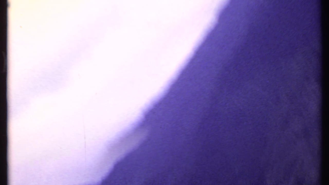 Overexposed 8mm frame from the 1969 India clip, dominated by pale light and purple color shift with minimal visible scenery.