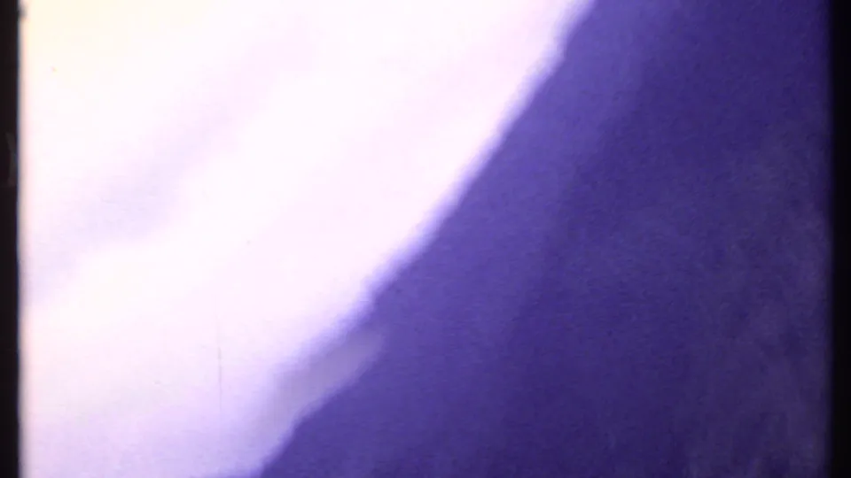 Overexposed 8mm frame from the 1969 India clip, dominated by pale light and purple color shift with minimal visible scenery.