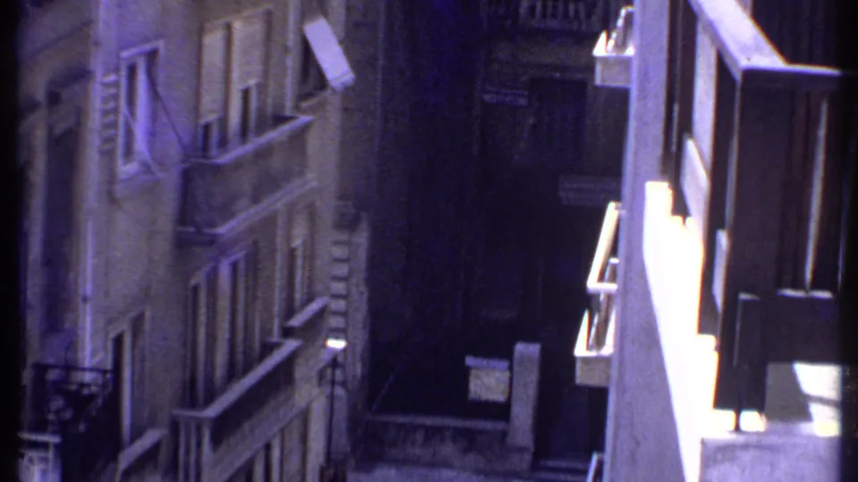 1969 Kenya frame showing bright white balcony edges against darker concrete facades and a narrow shadowed urban passage.