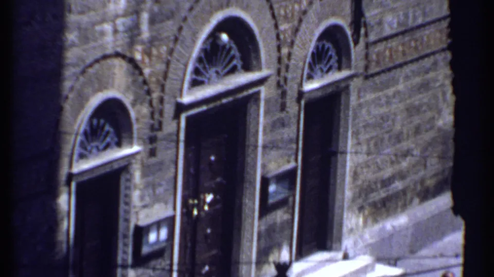Stone church-like exterior in Kenya with tall arched openings, fanlight window details, and dark doorway areas.