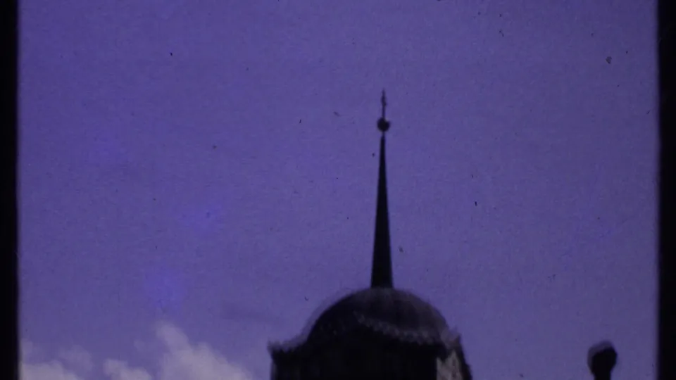 1969 Kenya home-movie frame with a tall spire, partial domed tower, and small chimney-like form against open sky.
