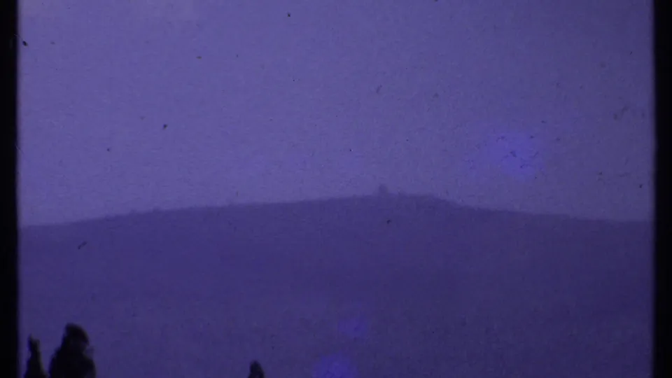 1969 Kenya 8mm frame with soft distant hills, faint valley detail, and dark tree tops near the bottom of the frame.