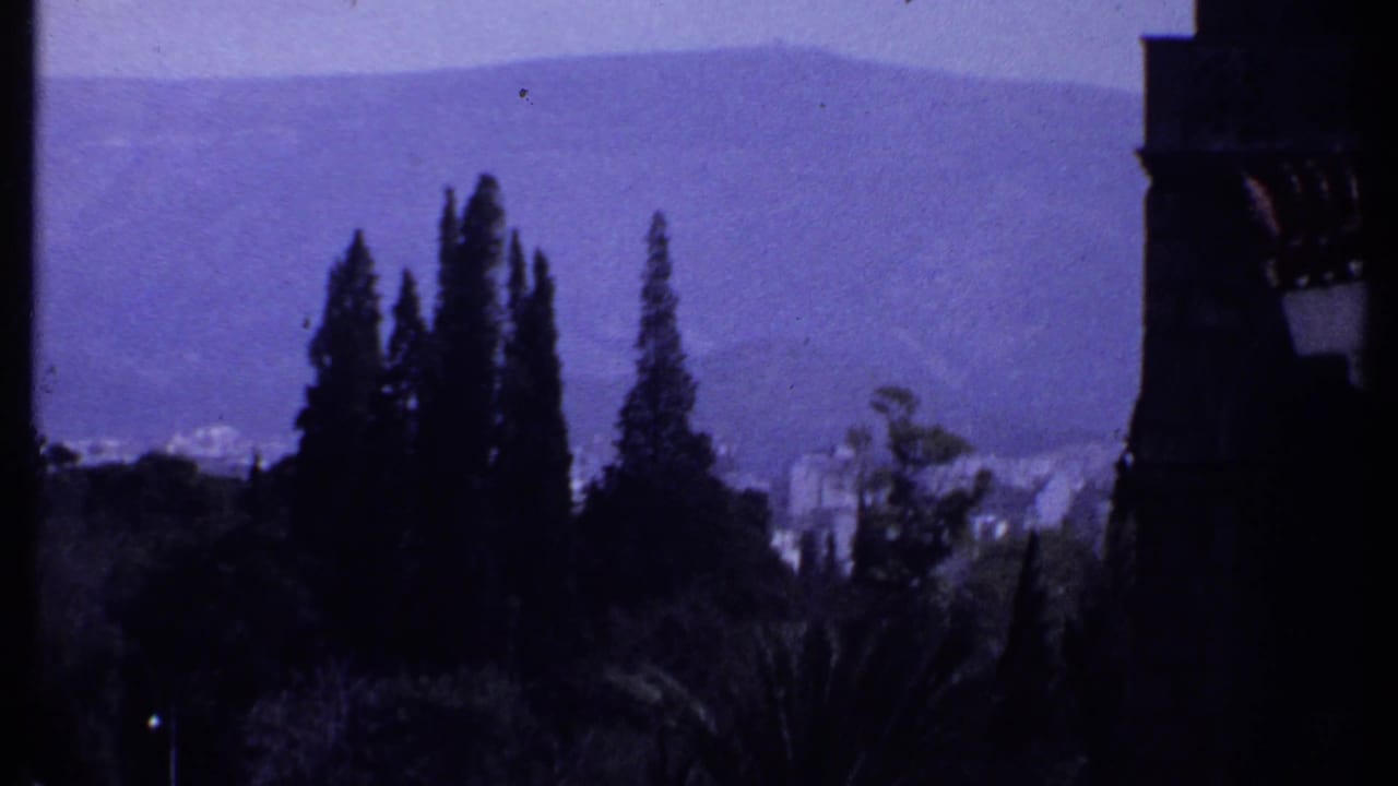 Distant hills and tall trees seen from a shaded balcony or arcade.