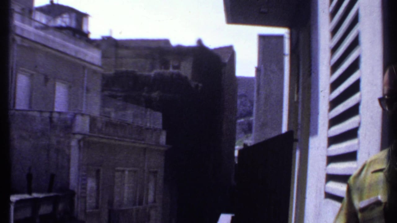 View from a balcony toward weathered city buildings and shuttered windows.