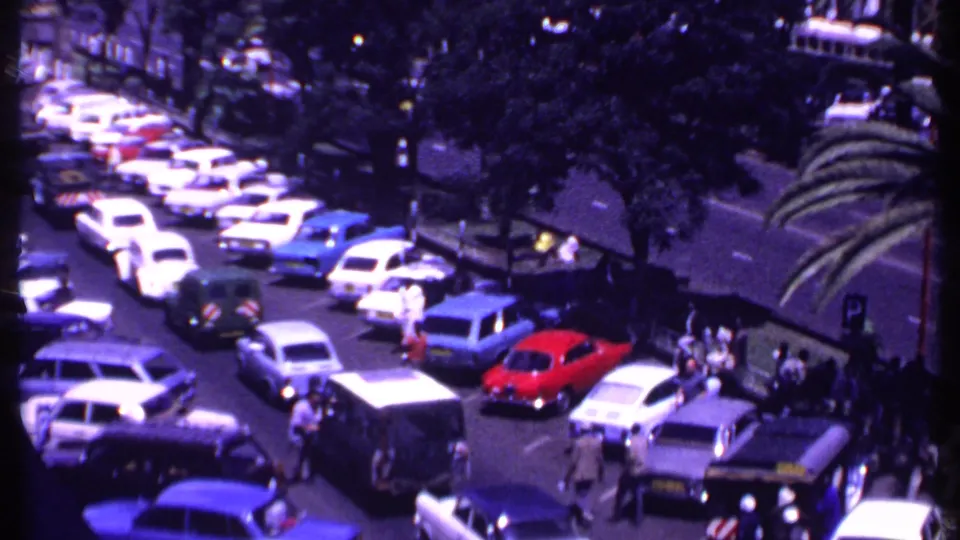 1969 Kenya street scene with congested traffic, pedestrians near the curb, parked cars, and palms from an elevated angle.