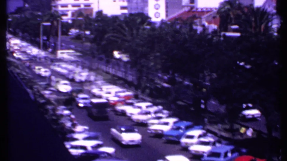 Elevated 1969 Kenya view of a crowded roadway, palm trees, sidewalks, and background buildings under bright daylight.