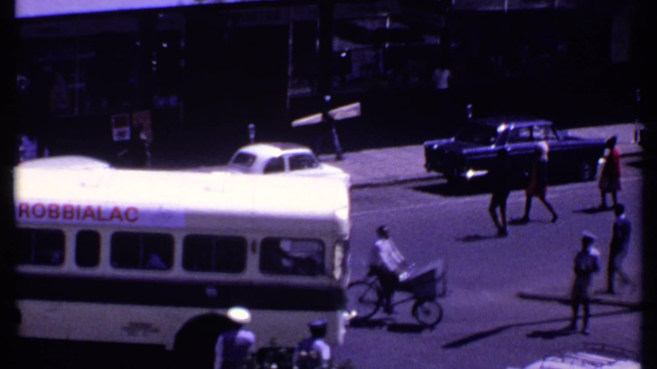 Bus in traffic as a cargo cyclist and pedestrians move through the street.