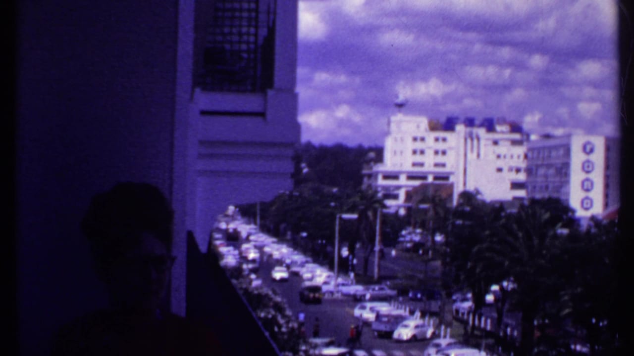 Dark balcony foreground looking toward a busy street and city buildings.
