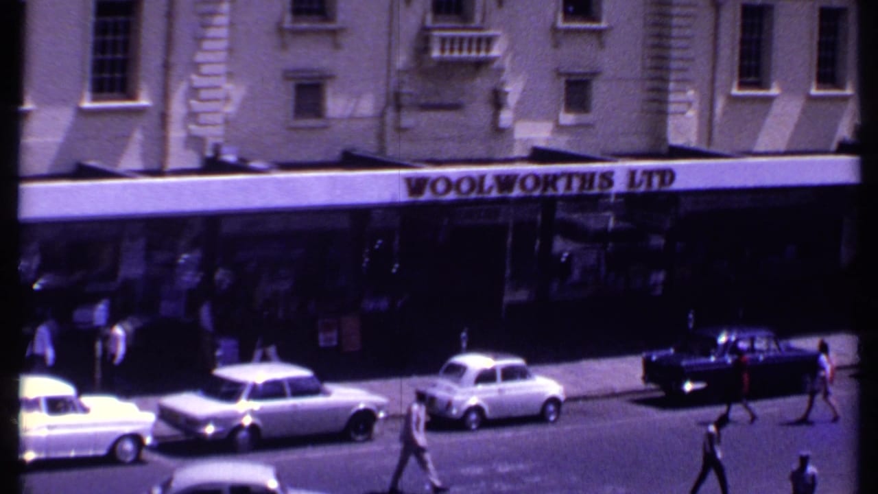Closer street view of the Woolworths Ltd frontage with cars and people nearby.