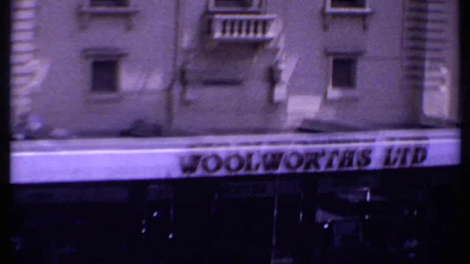 A closer 1969 Kenya frame centers the Woolworths Ltd sign and upper storefront, with the building facade and partial street activity at the edges.
