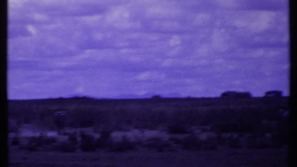 Purple-shifted 8mm frame of Kenyan savannah with distant tree shapes along the horizon.