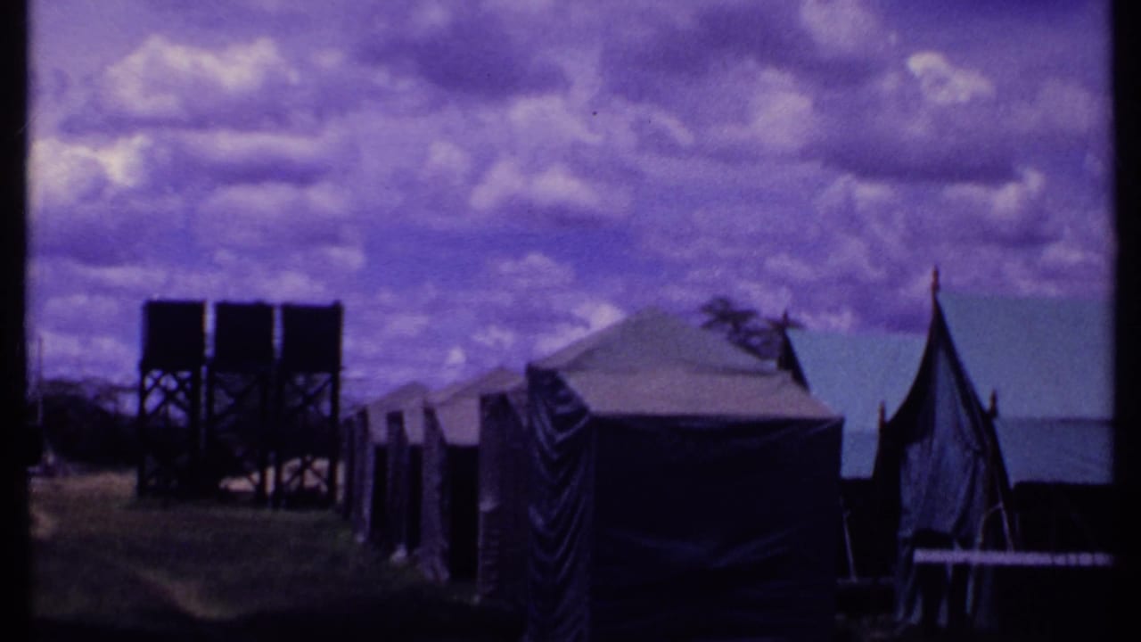Camp tents and twin elevated water tanks viewed across grass.