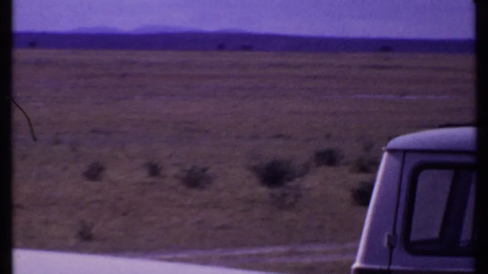 Kenya 1969 landscape view with broad scrubland, distant ridge, and the edge of a vehicle visible on the right.