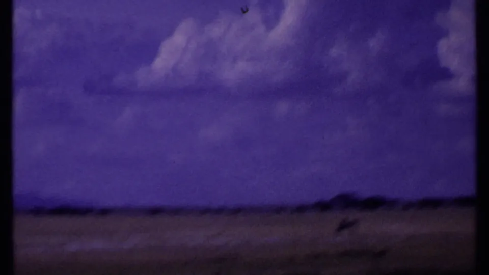 Kenya 1969 travel footage shifts to a low, soft-focus view of open ground, sky, and distant terrain from a moving vehicle.