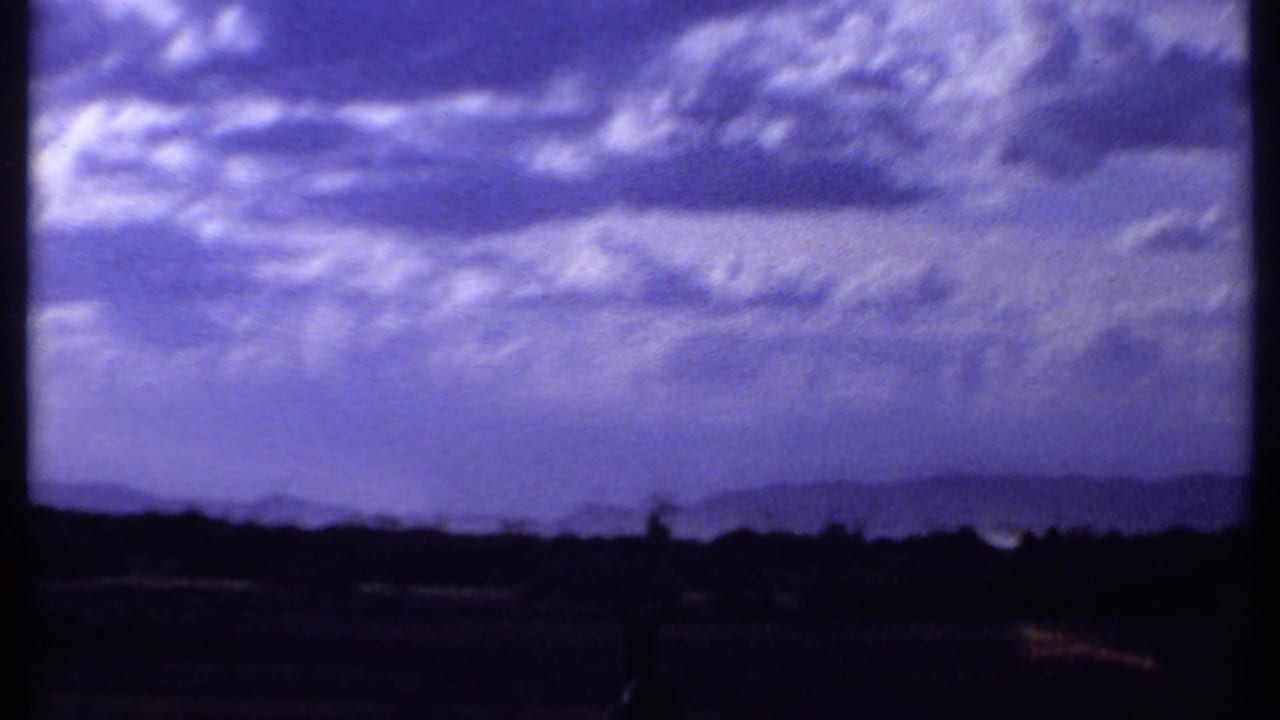 1969 Kenya 8mm frame shifting from wildlife to a wide purple-tinged sky over dark distant hills and land.