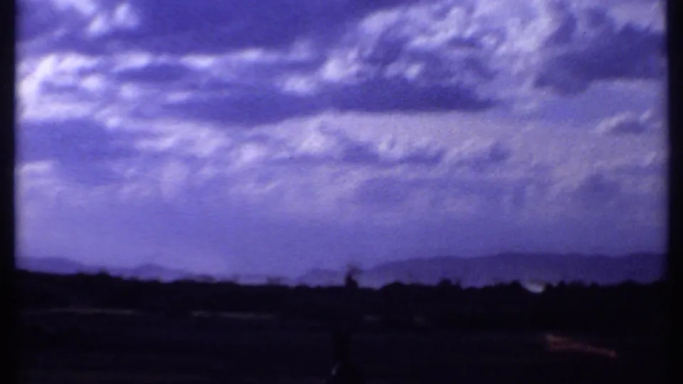 1969 Kenya 8mm frame shifting from wildlife to a wide purple-tinged sky over dark distant hills and land.