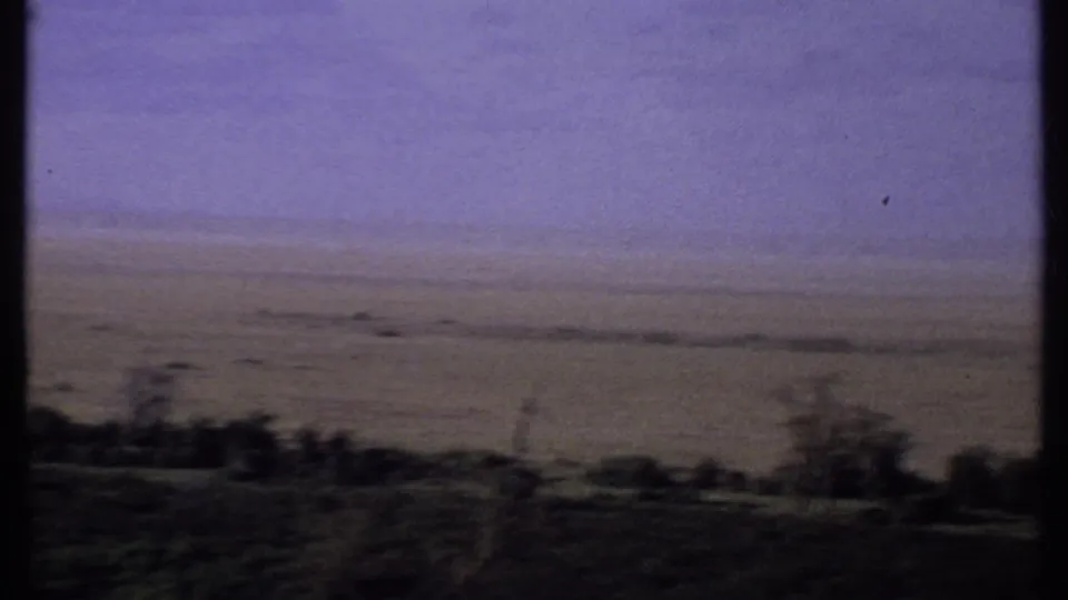 1969 Kenya 8mm view of an expansive savanna horizon with dark tree silhouettes and muted earth tones.