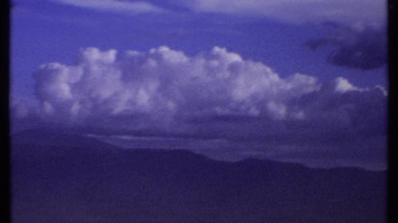 The final 1969 Kenya frame leaves the people and holds on purple-blue clouds, distant ridges and a broad valley landscape.