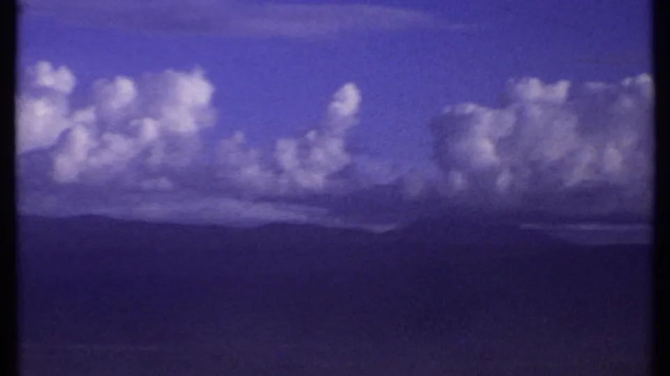 1969 Kenya 8mm frame with a broad cumulus cloud bank above layered, distant mountain silhouettes.