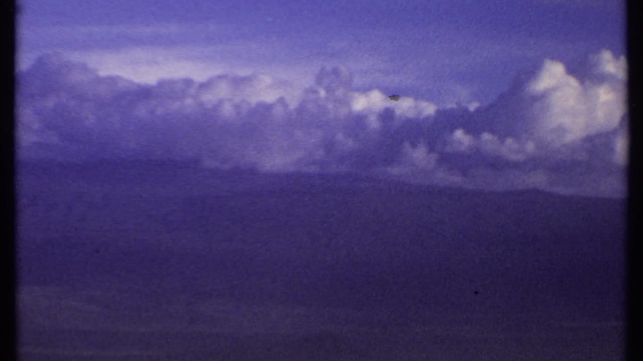 Dark cloud bank beneath a purple-blue sky with soft 8mm grain.