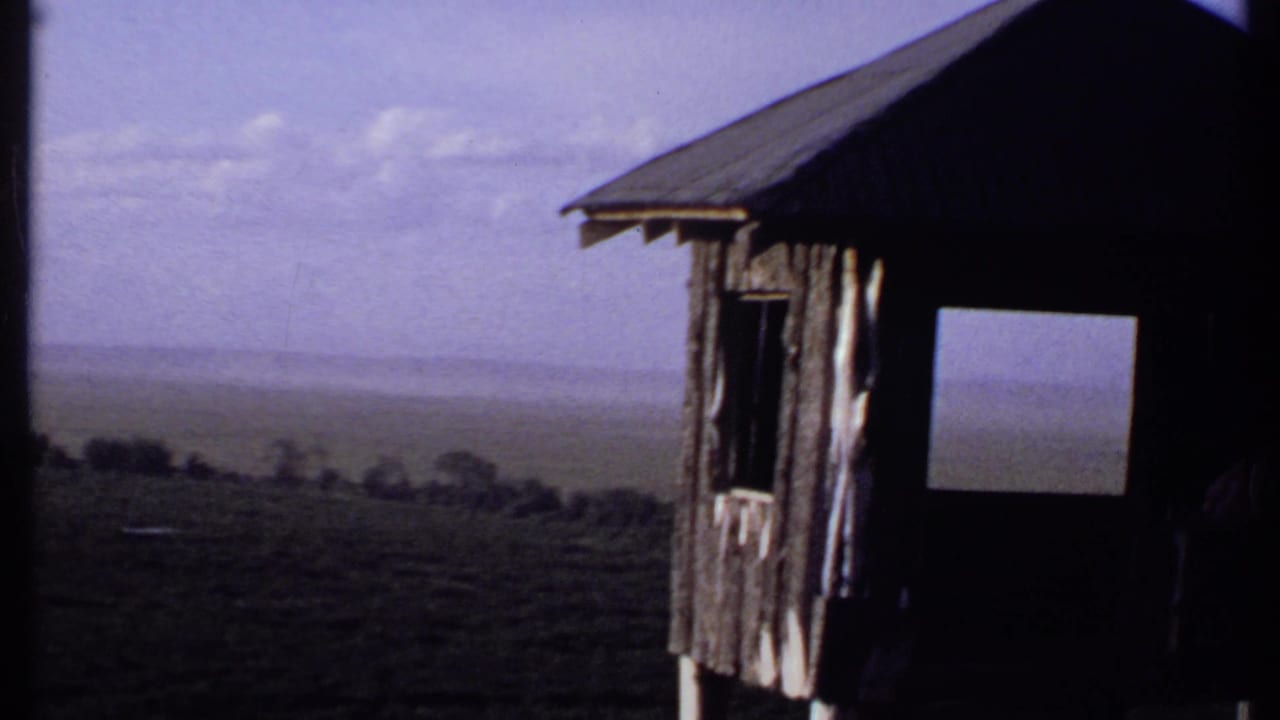 1969 Kenya 8mm view from a lookout area, with the shelter edge at right and open hazy plain beyond.