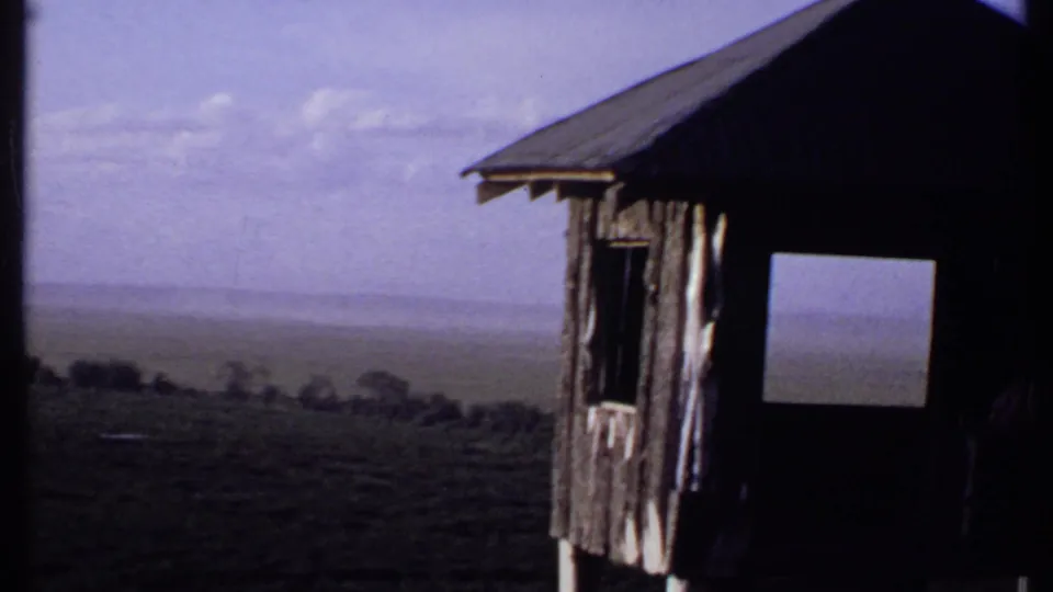 1969 Kenya 8mm view from a lookout area, with the shelter edge at right and open hazy plain beyond.
