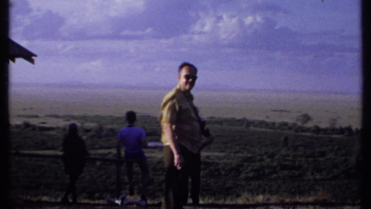 In Kenya 1969 footage, a man in sunglasses turns back toward the camera while others continue facing the distant view.