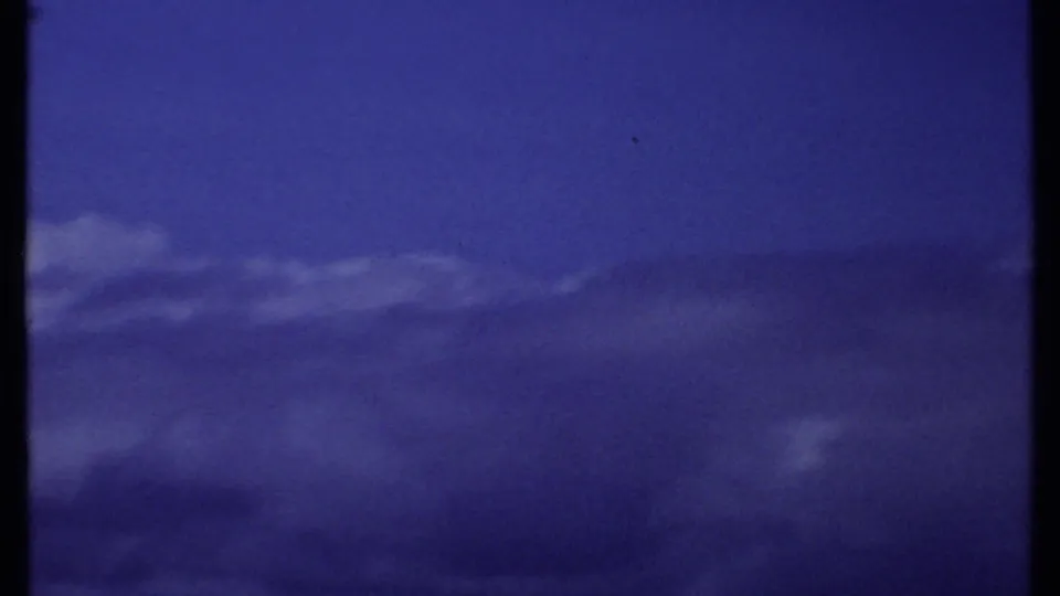 1969 Kenya 8mm aerial cloudscape with the mountain largely hidden or outside the frame beneath a saturated blue sky.