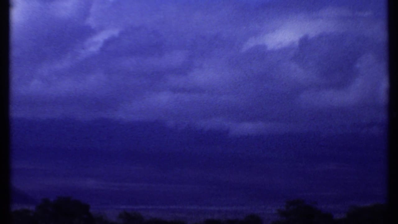 Cloudy blue sky over a low dark horizon with trees at the bottom edge.