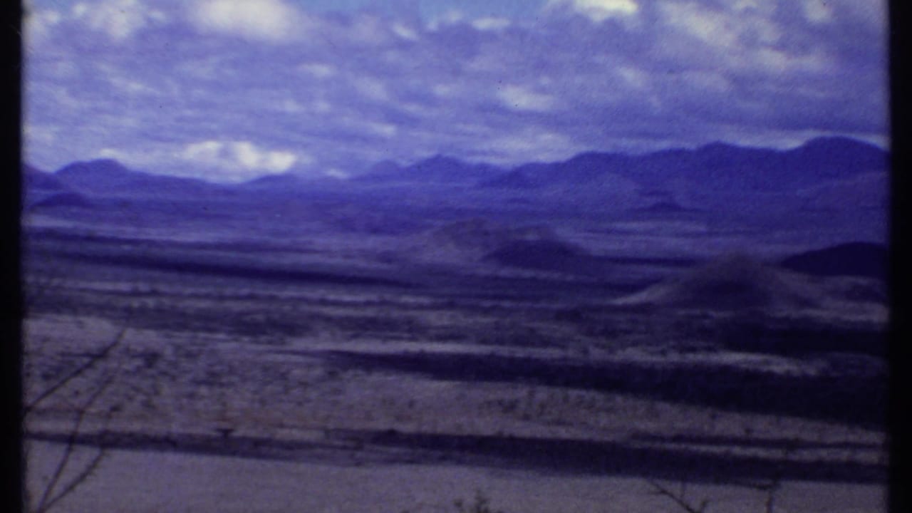 Panoramic mountain landscape with dry valley and clouded sky.
