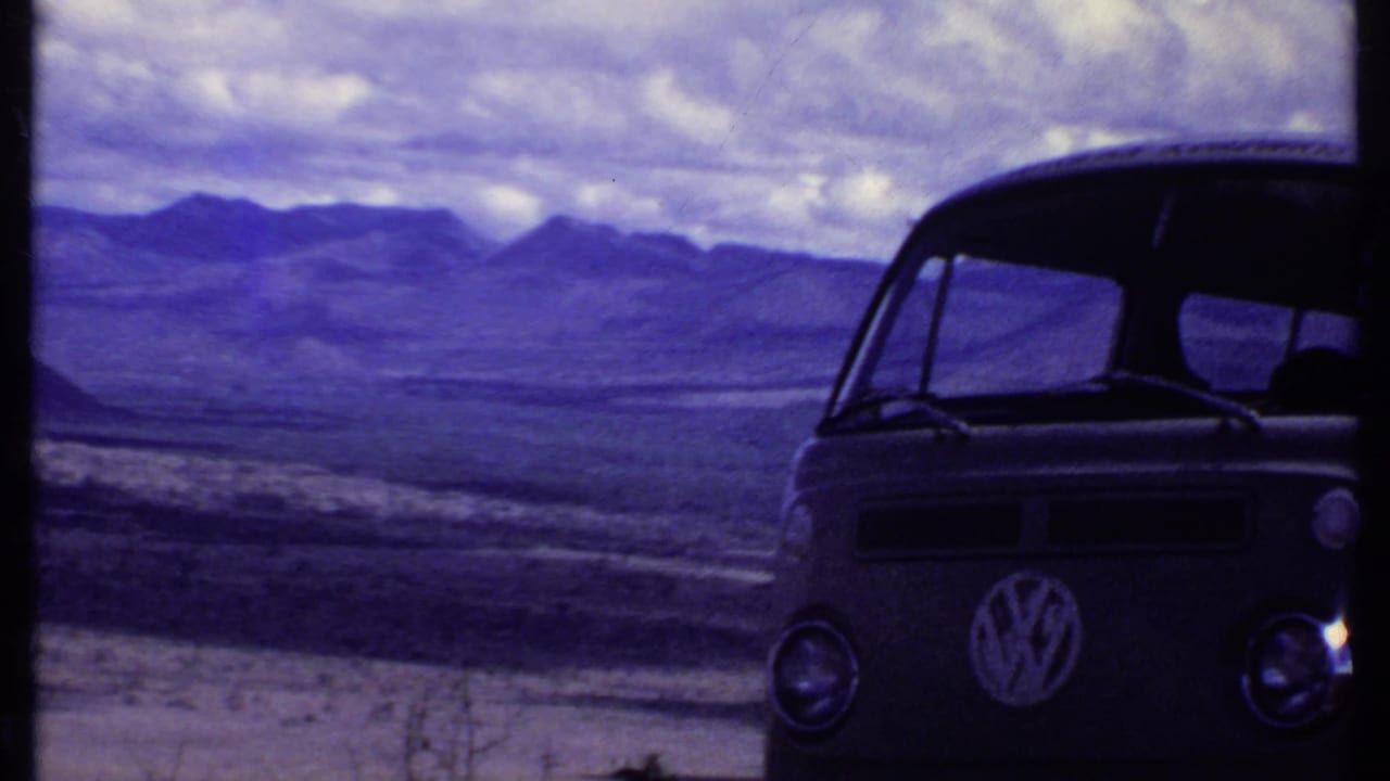 1969 Kenya home-movie frame with the front of a Volkswagen bus at right and dry mountain landscape beyond.