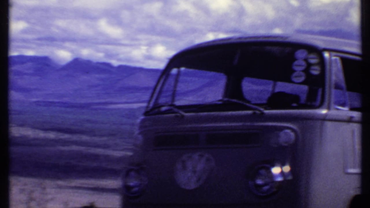 Kenya 1969 home-movie frame showing the front of a Volkswagen bus parked in open arid terrain beneath a cloudy sky.