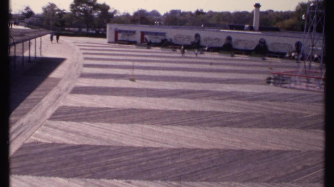 Wide 1969 New London view of an open striped concrete surface with small figures near a mural-fronted building and metal tower.