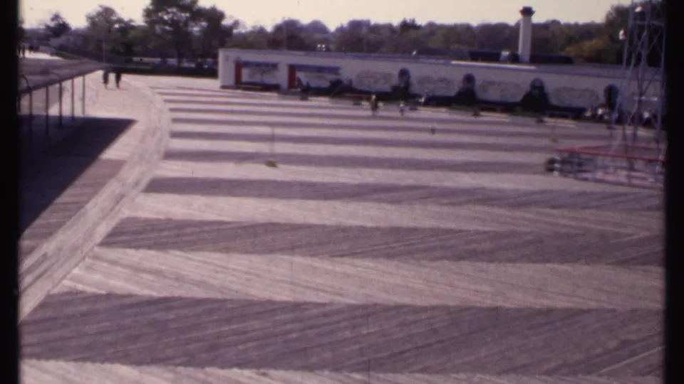 Wide 1969 New London view of an open striped concrete surface with small figures near a mural-fronted building and metal tower.