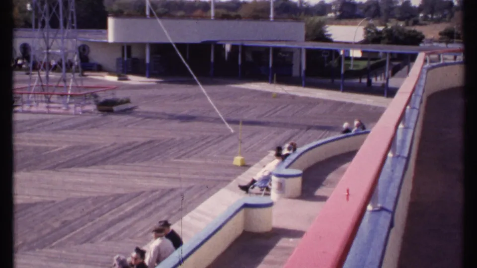 1969 New London 8mm frame with spectators on curved concrete seating overlooking a wooden deck and metal tower area.
