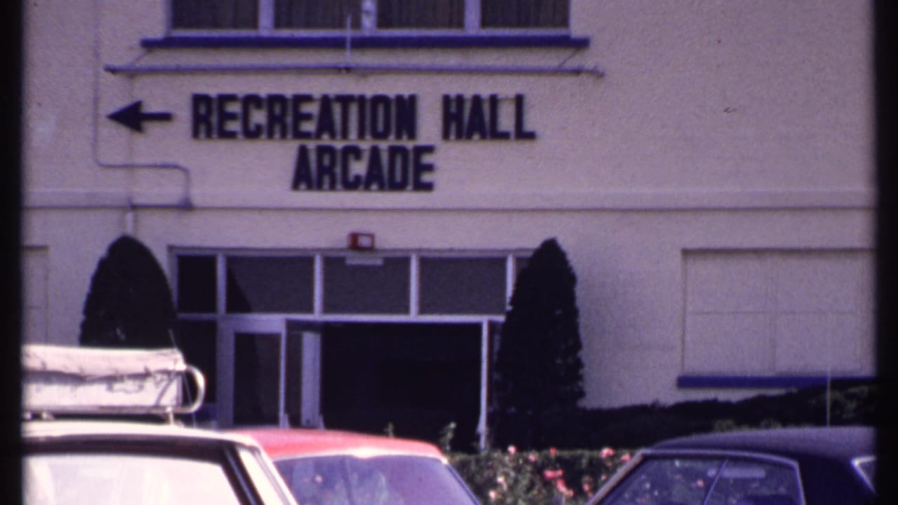 Recreation Hall Arcade sign above entrance doors with cars parked in the foreground.