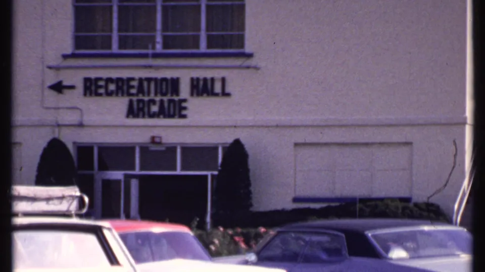 1969 New London exterior showing Recreation Hall Arcade lettering above cars in a sunlit parking area.