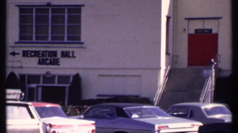 New London Recreation Hall Arcade building with parked 1960s cars and a red side door at the top of steps.