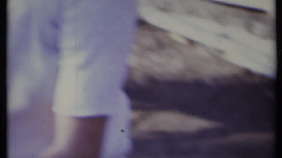 A blurred high-angle frame shows the puppy beside paper, with partial human presence at the edge of the home-movie scene.