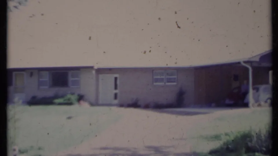 Soft 8mm view of a California suburban house exterior with a driveway leading toward a covered carport.