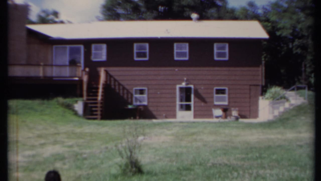Brown two-story house with exterior stairs and a grassy yard.
