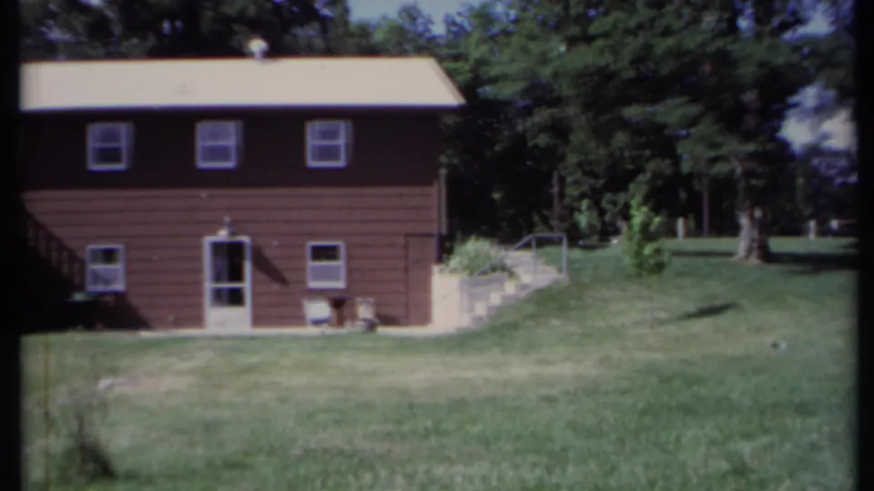 1971 California 8mm frame during a pan past the brown house toward the yard and trees.