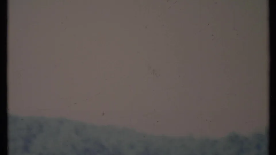Faded 1971 California 8mm frame where pale exposure washes over distant hills and faint tree shapes near the bottom.