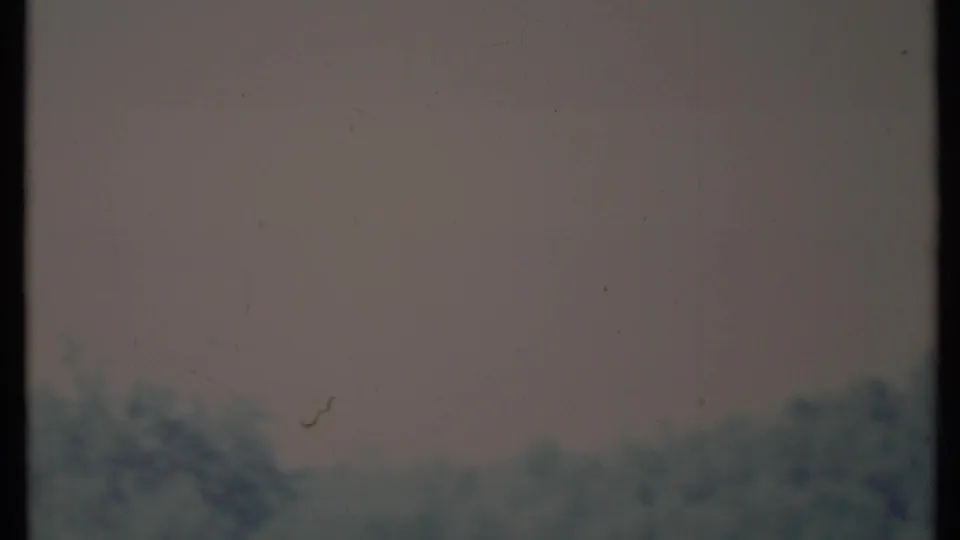 Faded 1971 California home-movie frame with blurred hillside forms, pale exposure, and visible film dust.